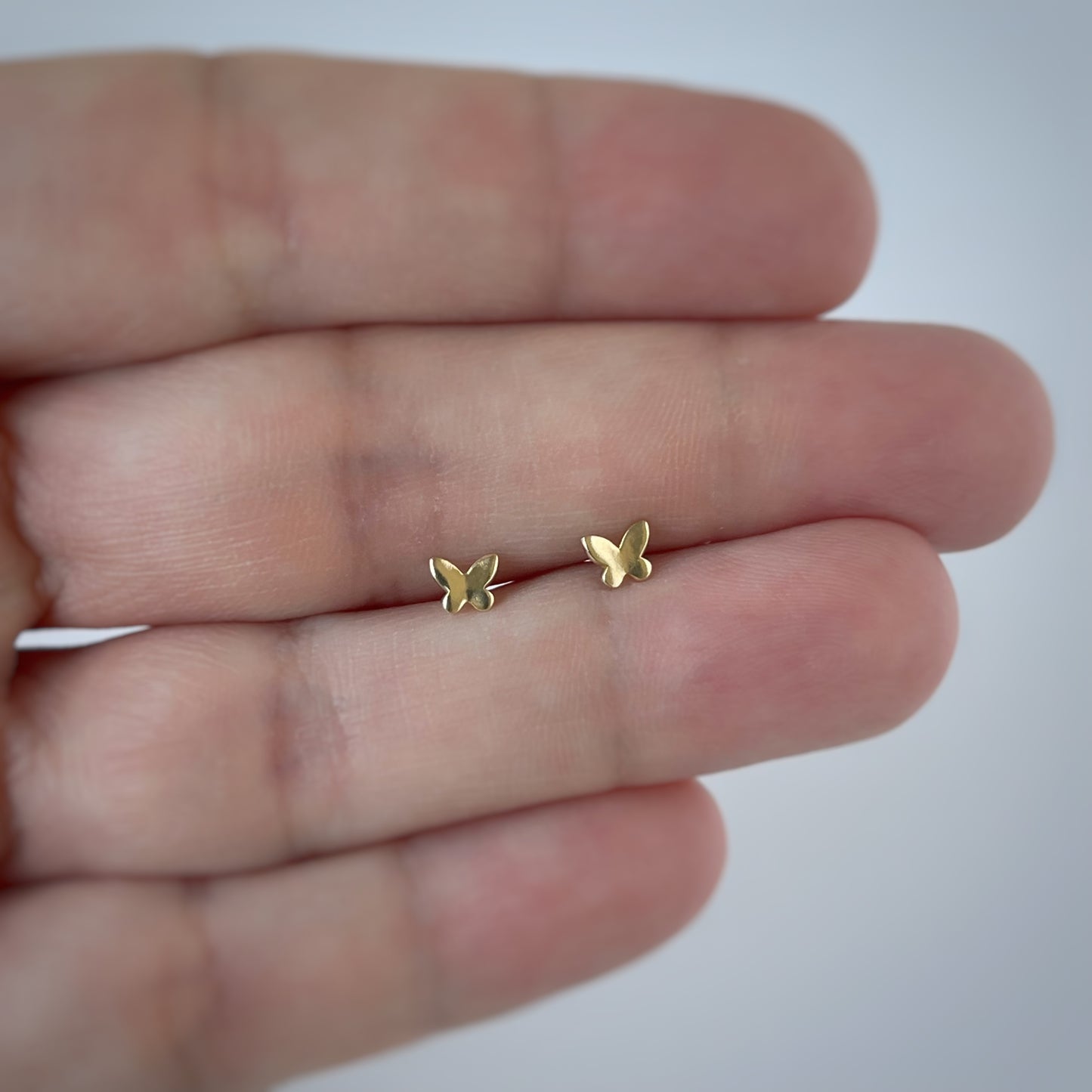 Aretes en oro amarillo 14K con mini mariposa en oro con tope rosca