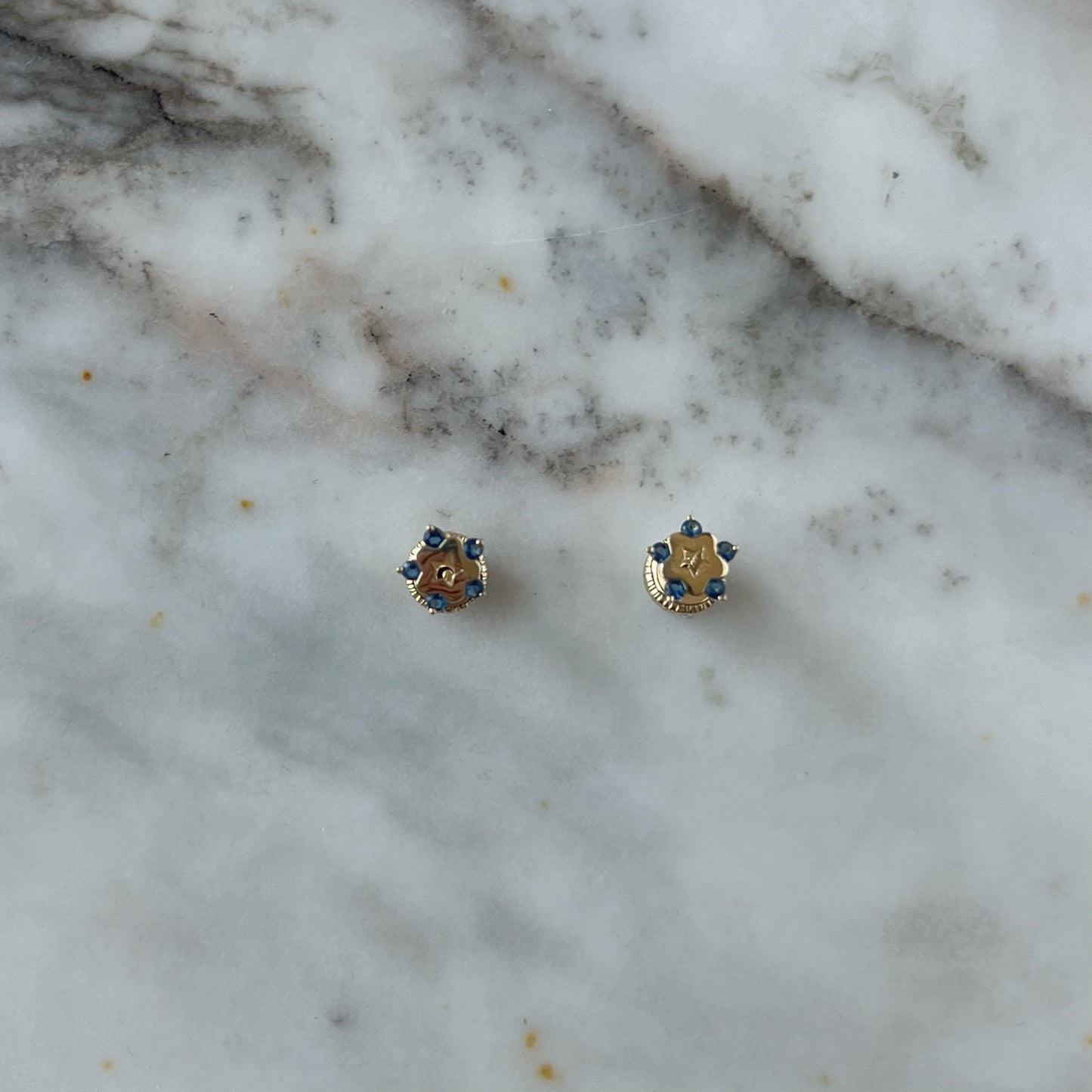 Aretes en oro amarillo de 14K con estrella tipo flor con circonita azul en los extremos y estrella calada en el centro con tope rosca