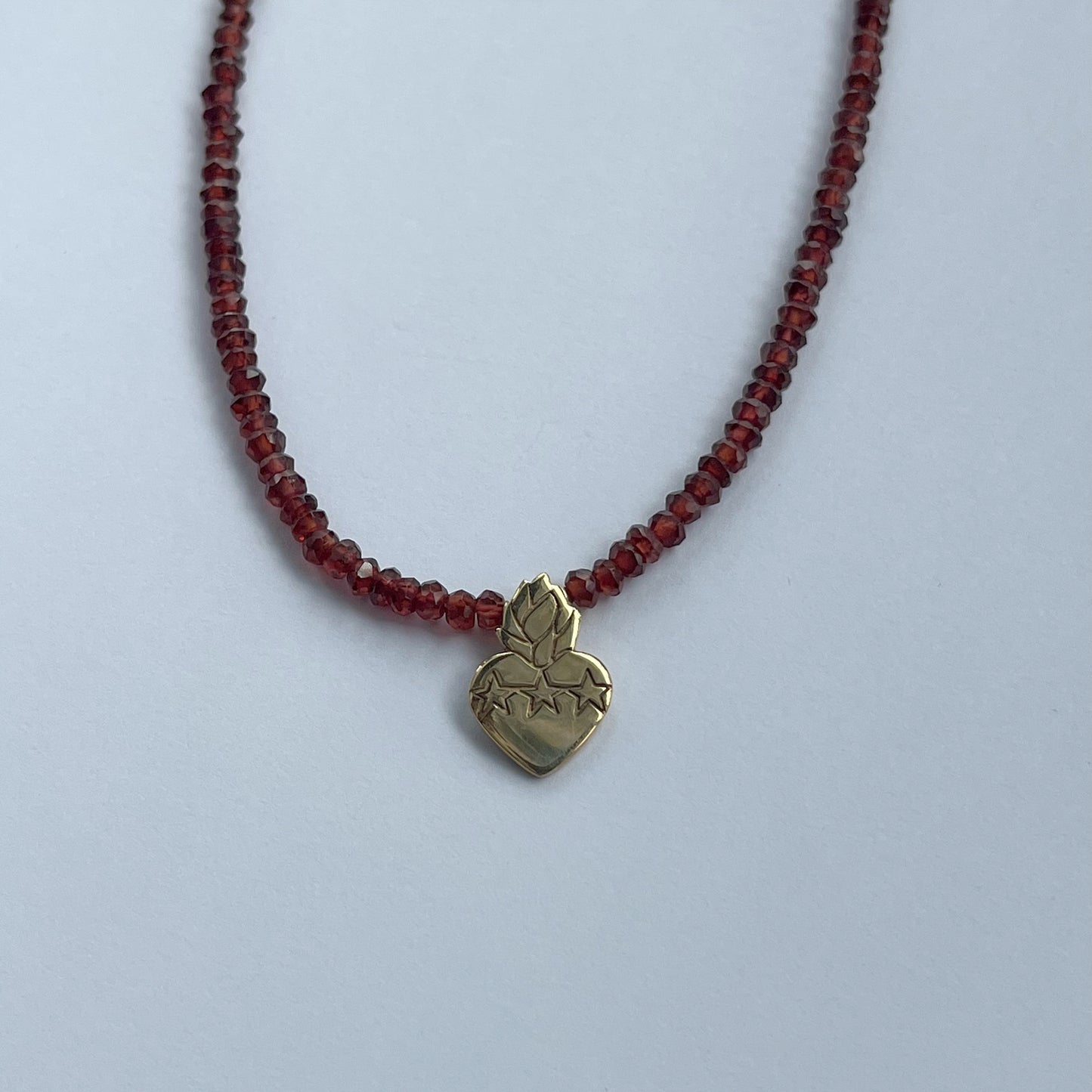 Collar de granates con sagrado corazón en plata con baño de oro amarillo y broche con cadena en goldfill