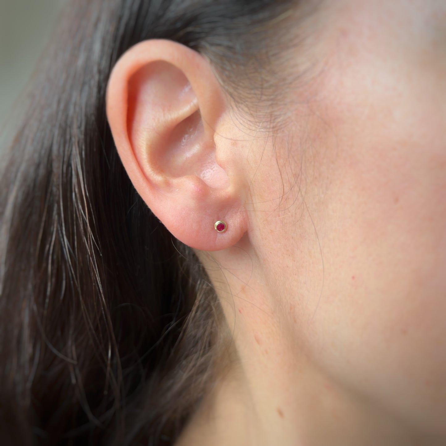 Aretes en oro amarillo 14k con circón biselado rojo con broche rosca