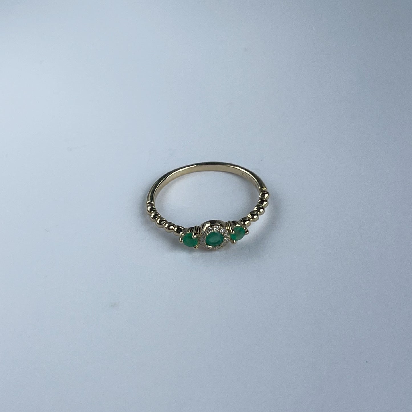 Anillo en oro amarillo 14k con tres esmeraldas redondas 0.25ctw y diamantes 0.04ct con aro de bolitas