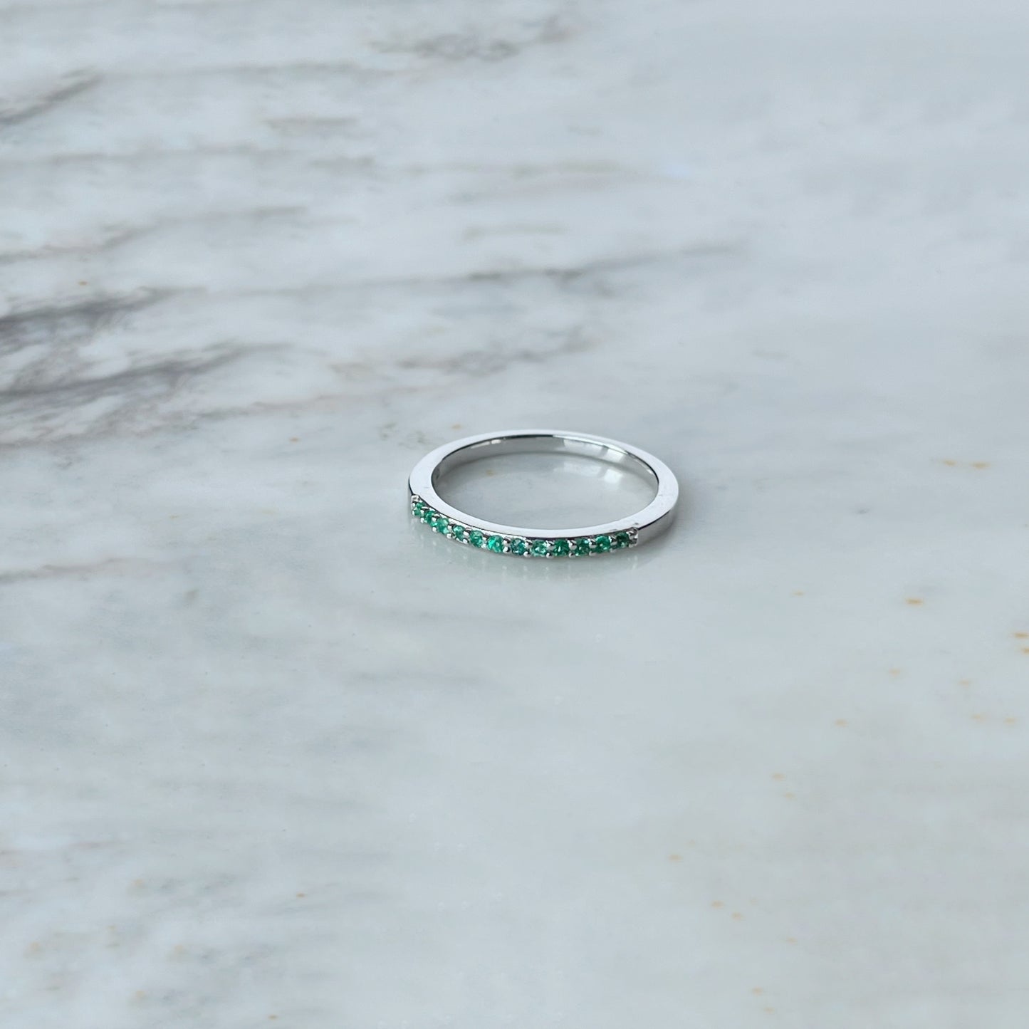 Anillo medio cintillo en oro blanco 14k con esmeraldas