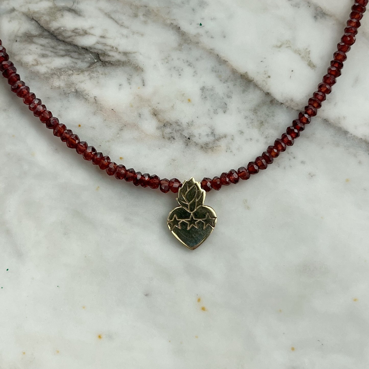 Collar de granates con sagrado corazón en plata con baño de oro amarillo y broche con cadena en goldfill