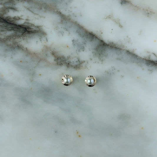 Arete en oro amarillo 14K con perla en el centro y círculo de rayitas de oro alrededor con tope rosca