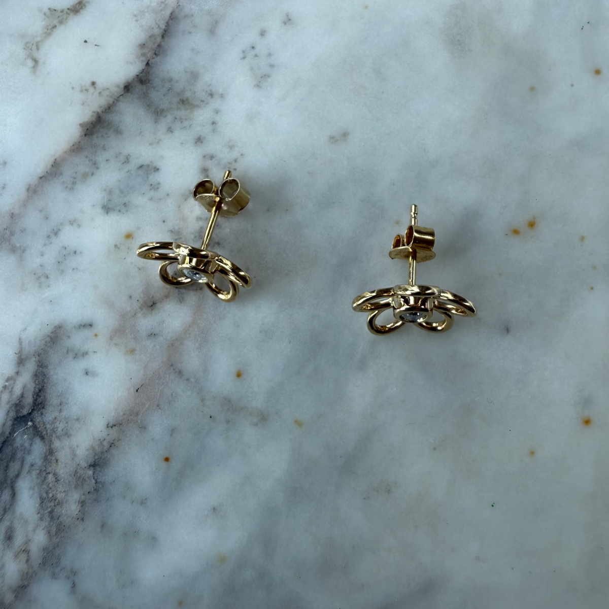 Aretes de flor delineada con diamante central 0.20ctw en plata con baño de oro