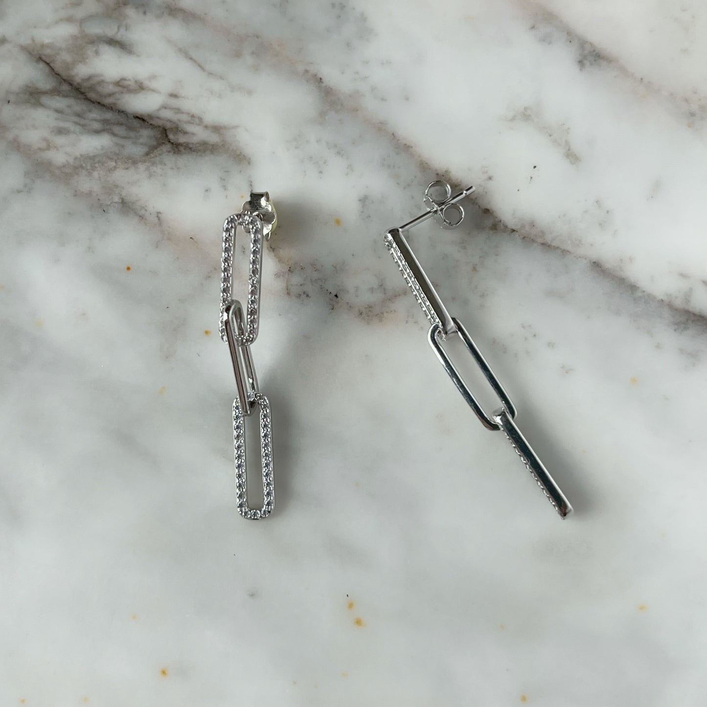 Arete largo paper clip de plata con baño platino y circonitas blancas