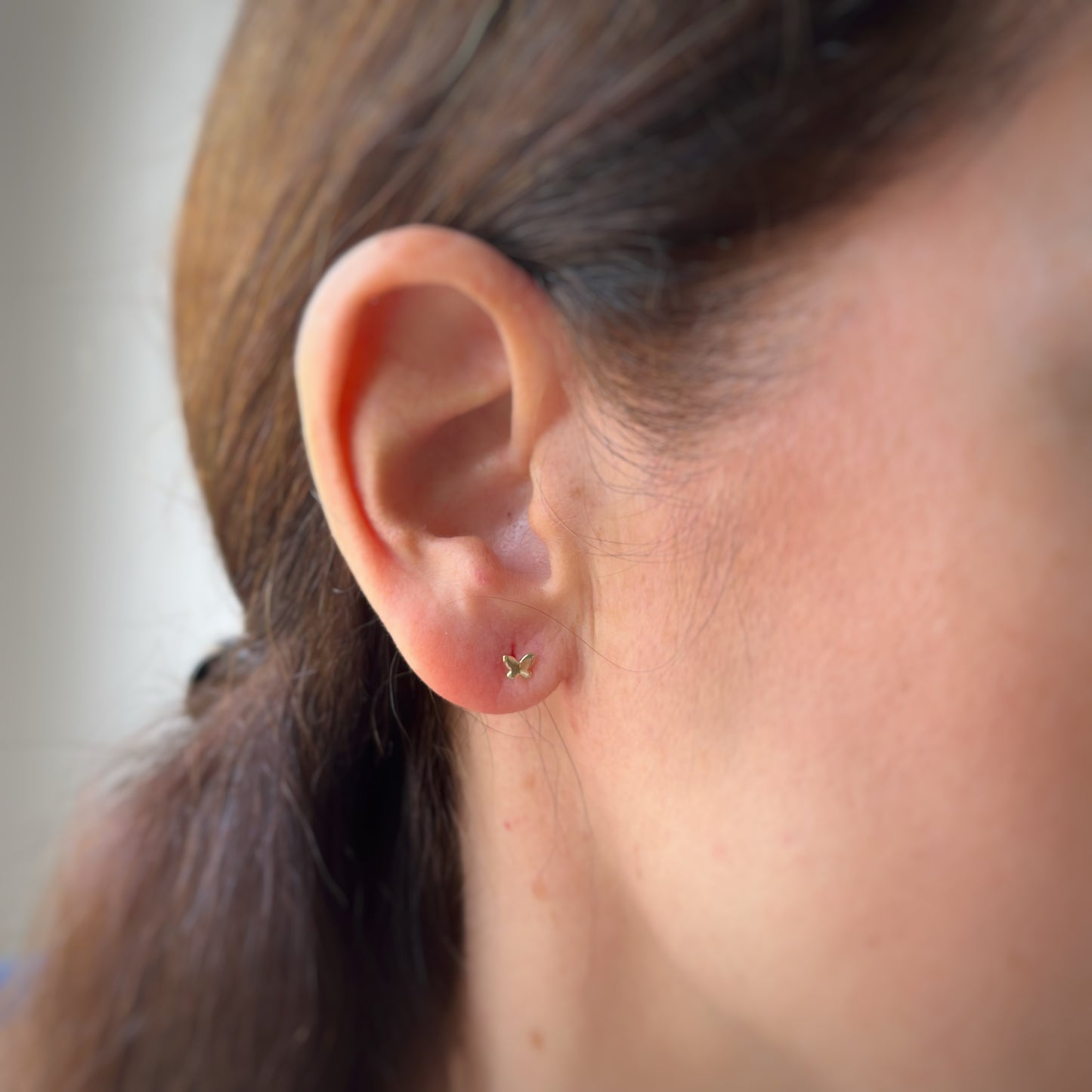 Aretes en oro amarillo 14K con mini mariposa en oro con tope rosca