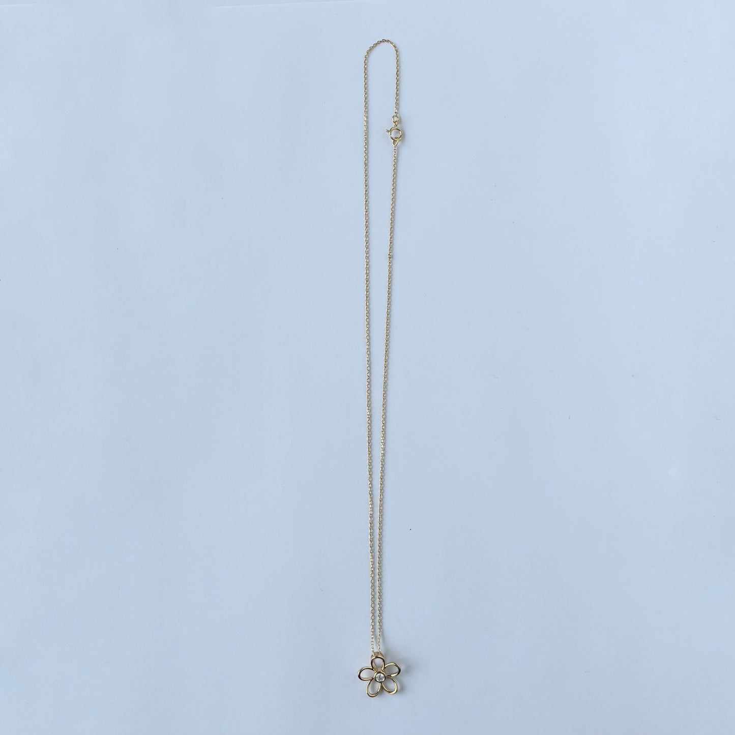 Collar en plata con baño de oro amarillo con dije de flor delineada y diamante central 0.10ct