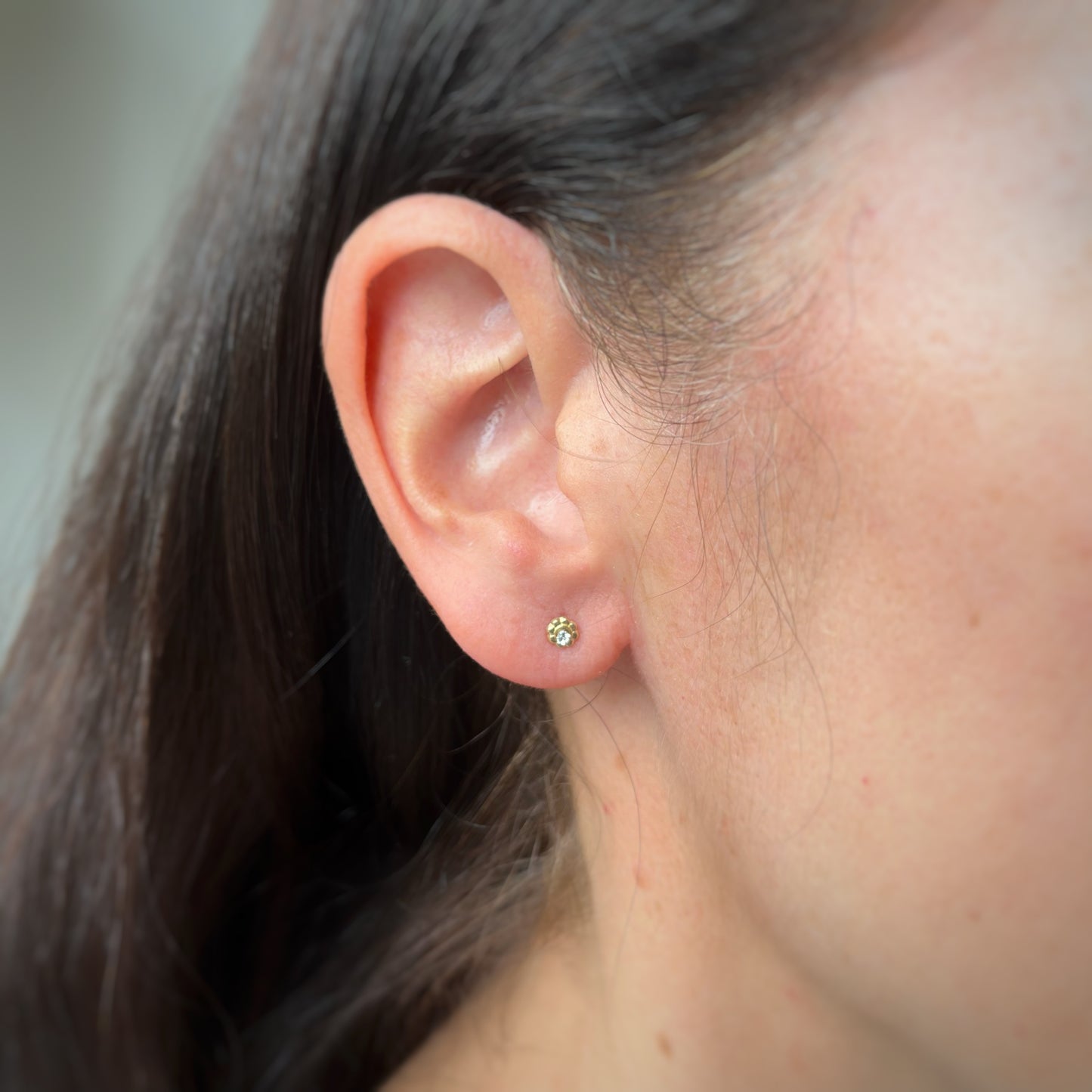 Aretes en oro amarillo 14k de flor mini con circón en el centro con broche rosca