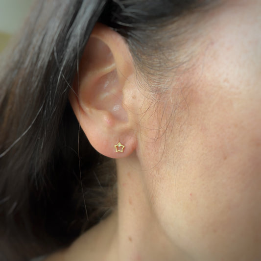Aretes en oro amarillo 18k estrellita delineada con diamante con broche rosca