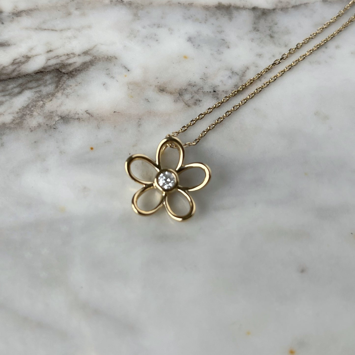Collar en plata con baño de oro amarillo con dije de flor delineada y diamante central 0.10ct