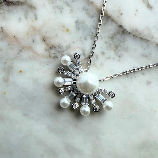 Collar de plata con baño platino y media flor de perla en el centro y circonitas blancas