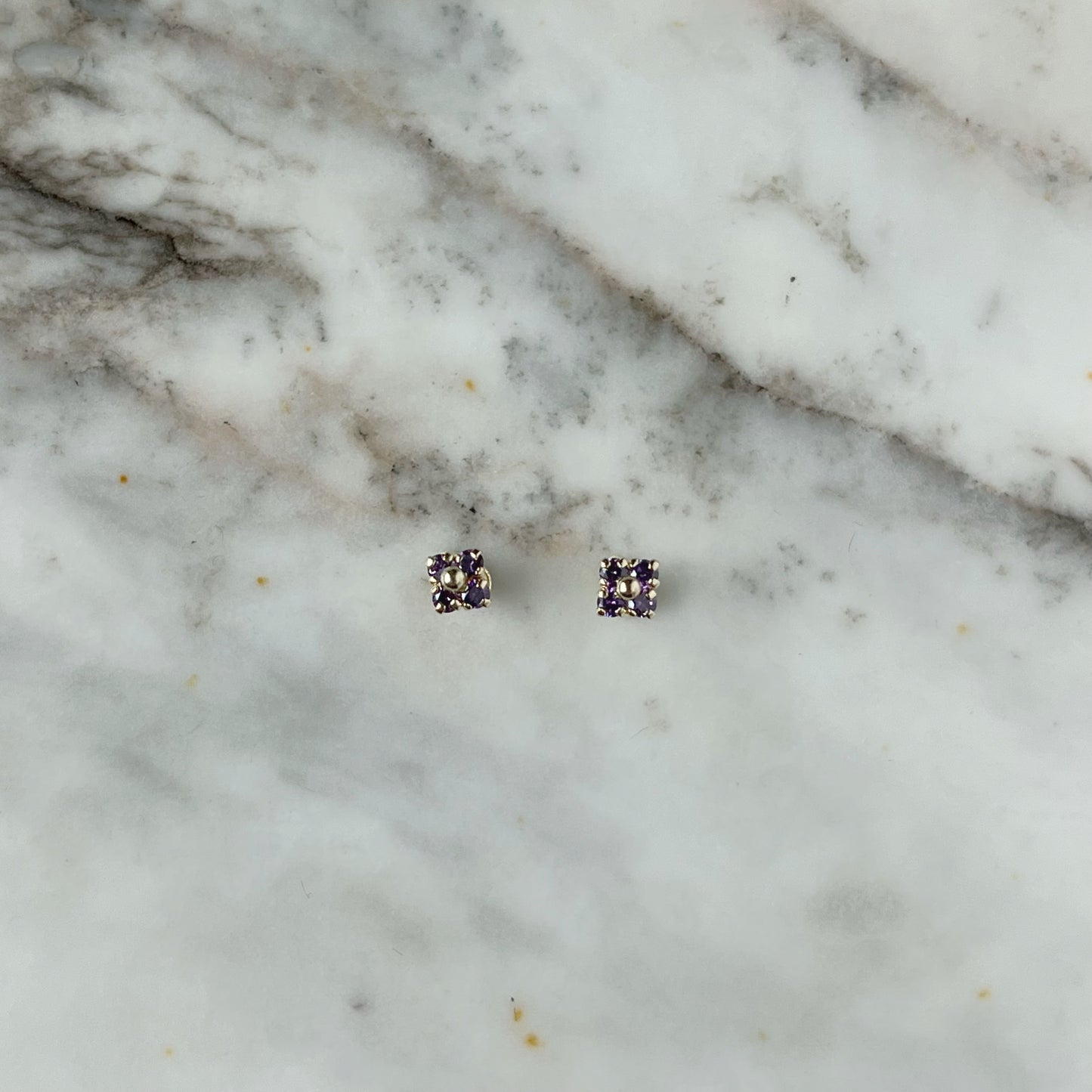 Aretes en oro amarillo 14k flores de circonitas morado con bolita de oro en el centro con broche rosca