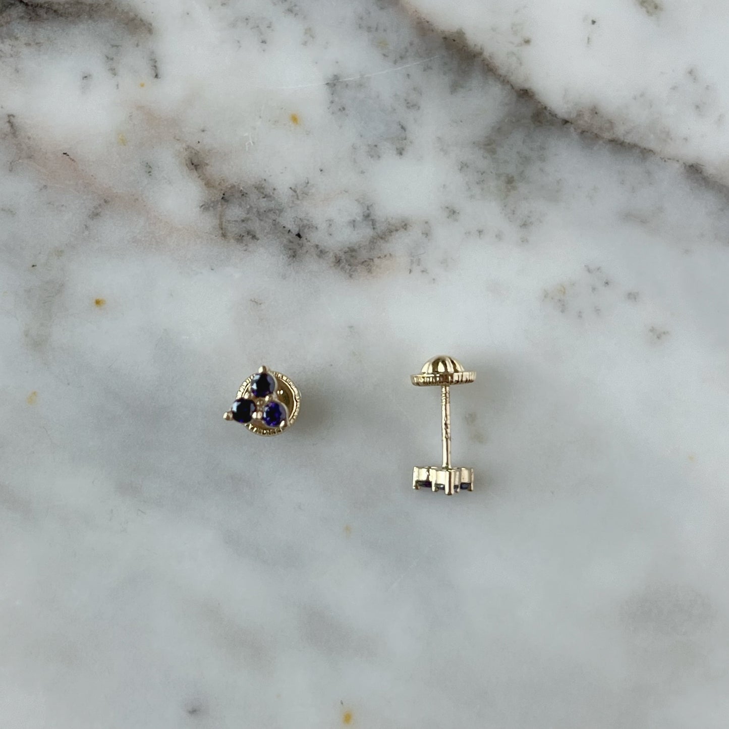 Aretes tres circonitas de color morado en oro amarillo de 14k con tope rosca