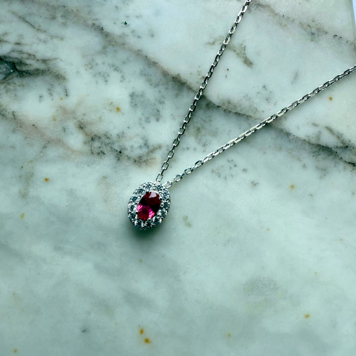 Collar de plata con baño platino y circonita ovalada roja con halo de circonitas blancas