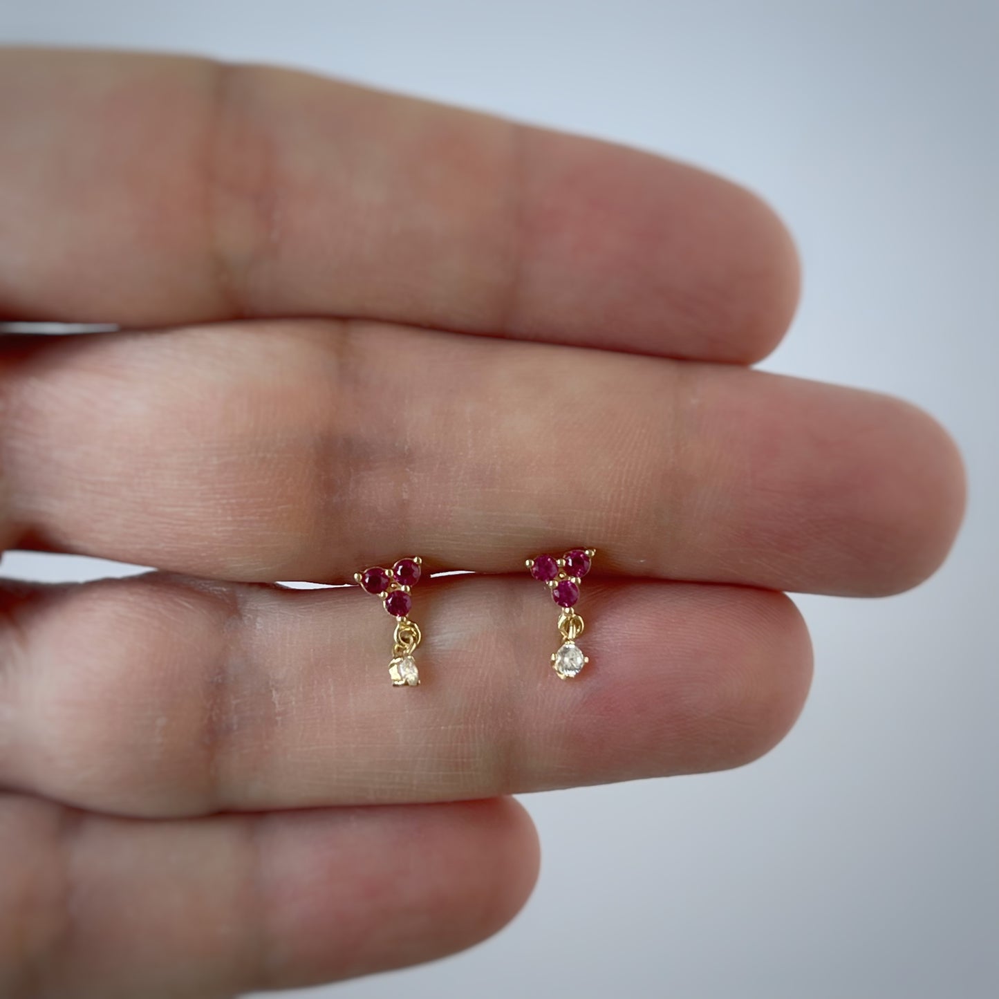 Arete con tres circonitas fucsia y una circonita colgante en oro amarillo de 14K con tope rosca