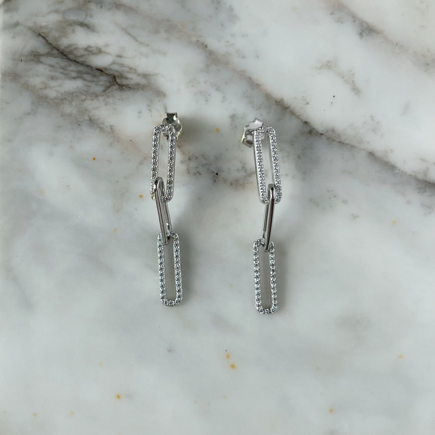 Arete largo paper clip de plata con baño platino y circonitas blancas