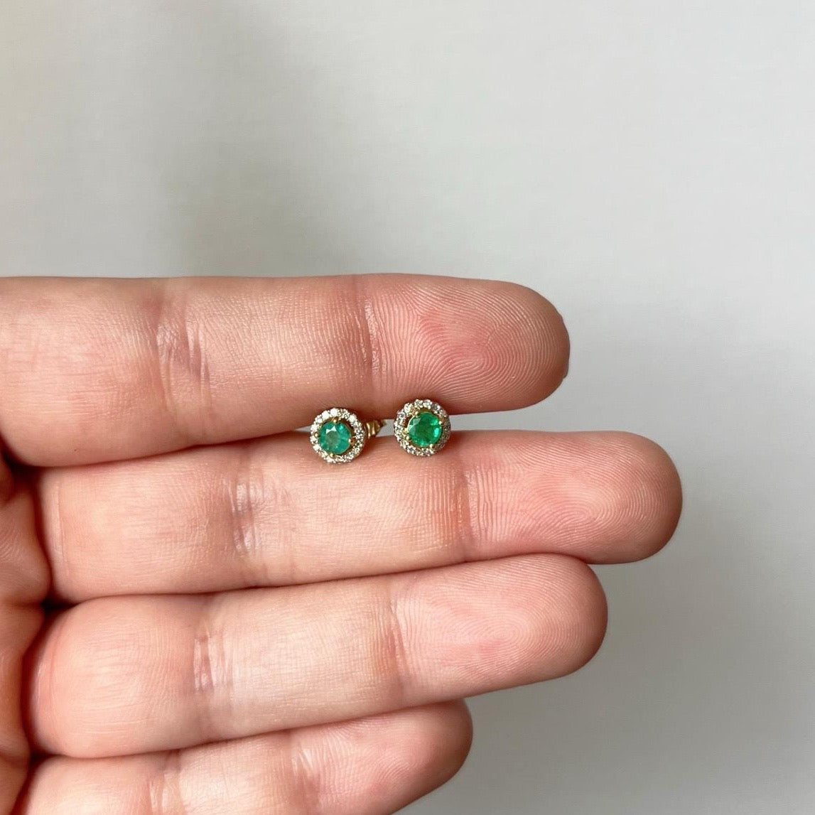 Aretes redondos en oro amarillo 10k con esmeraldas y halo de diamantes 0.10ctw