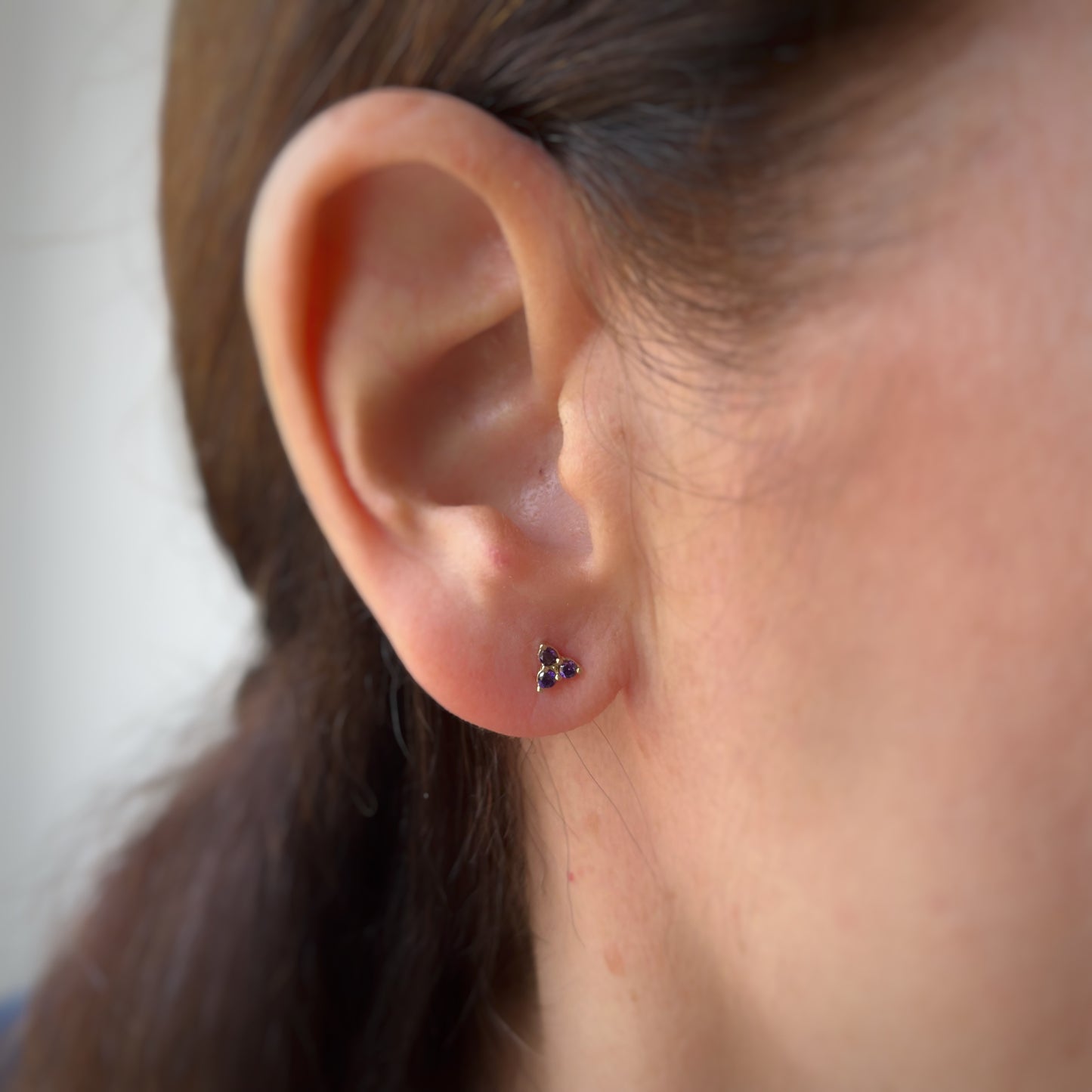 Aretes tres circonitas de color morado en oro amarillo de 14k con tope rosca