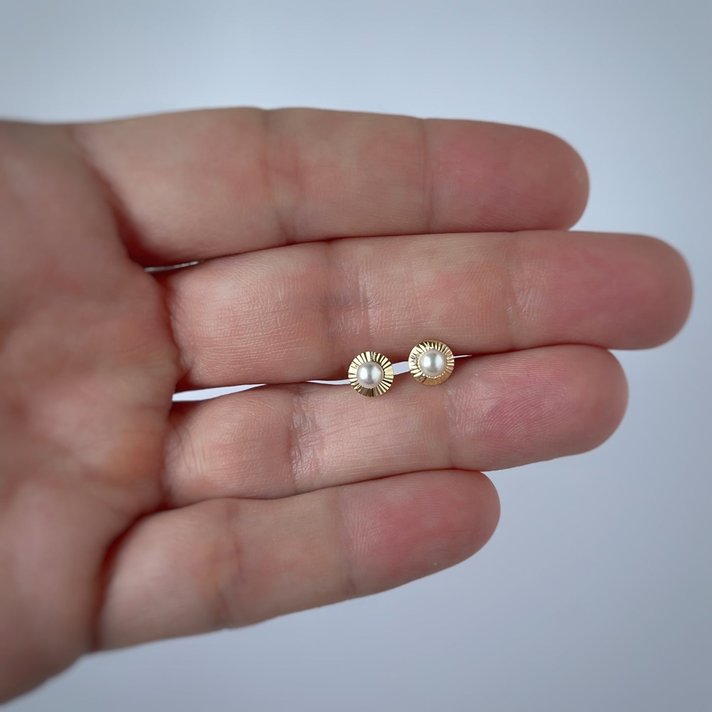 Arete en oro amarillo 14K con perla en el centro y círculo de rayitas de oro alrededor con tope rosca