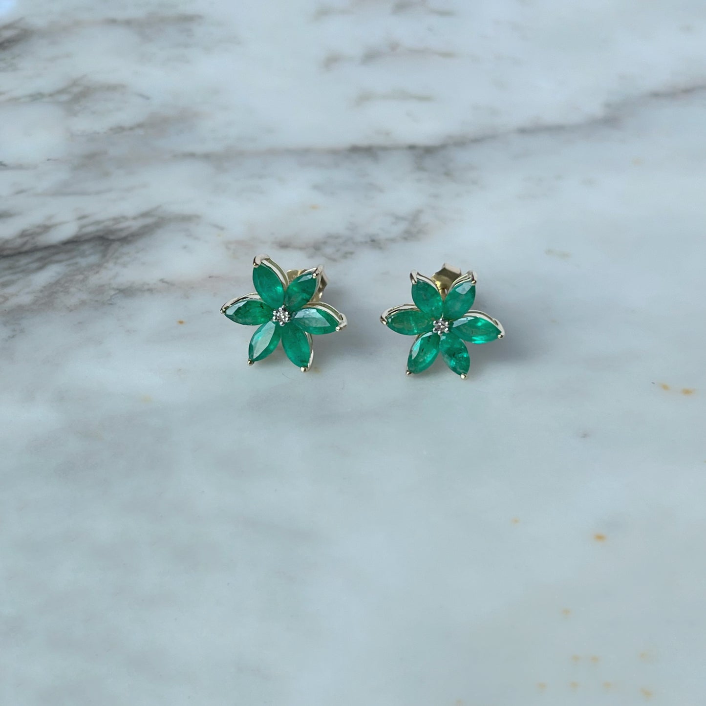 Aretes de flor de seis pétalos en oro amarillo 10K con esmeraldas y diamantes