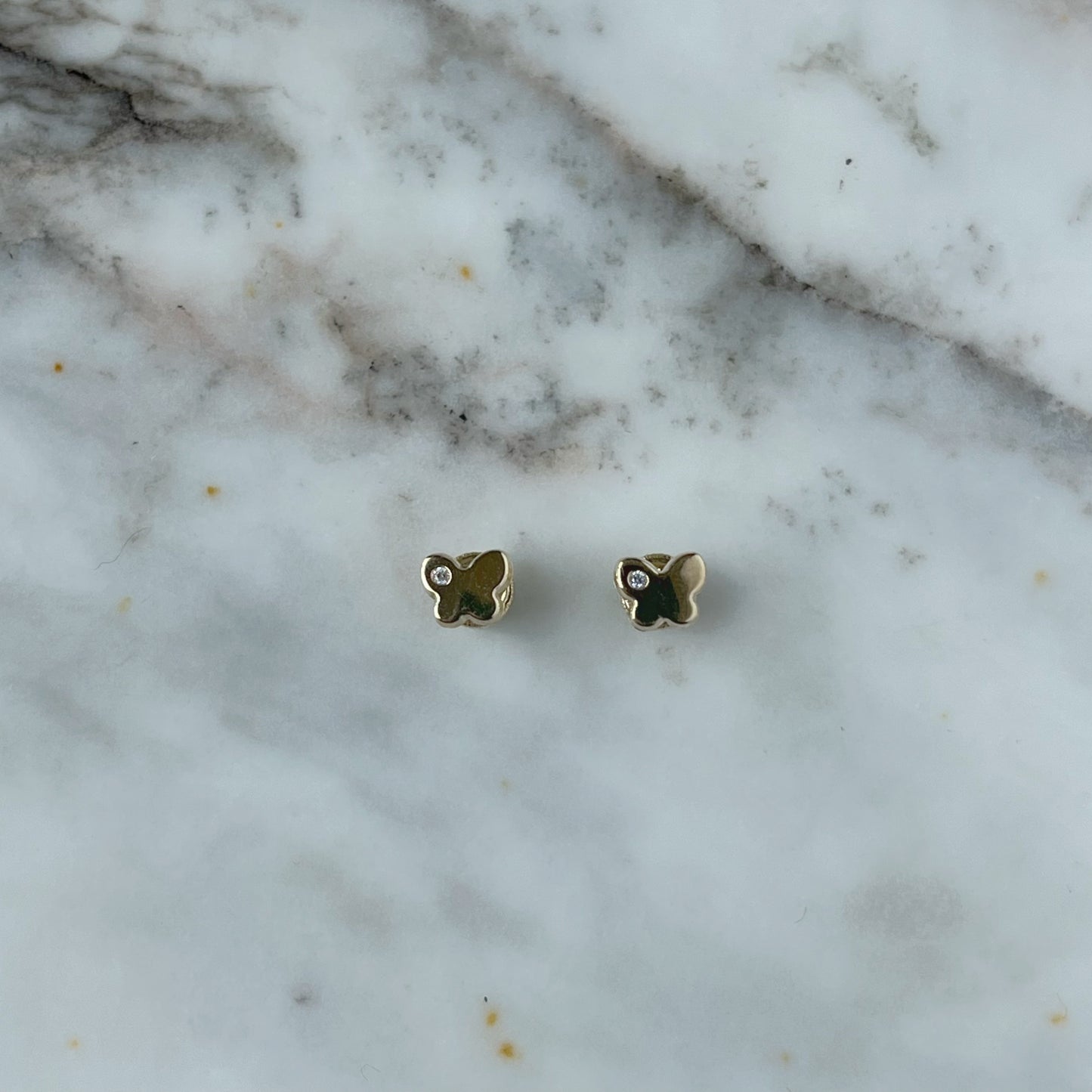 Aretes en oro amarillo 14k con mariposita y un circón con broche rosca