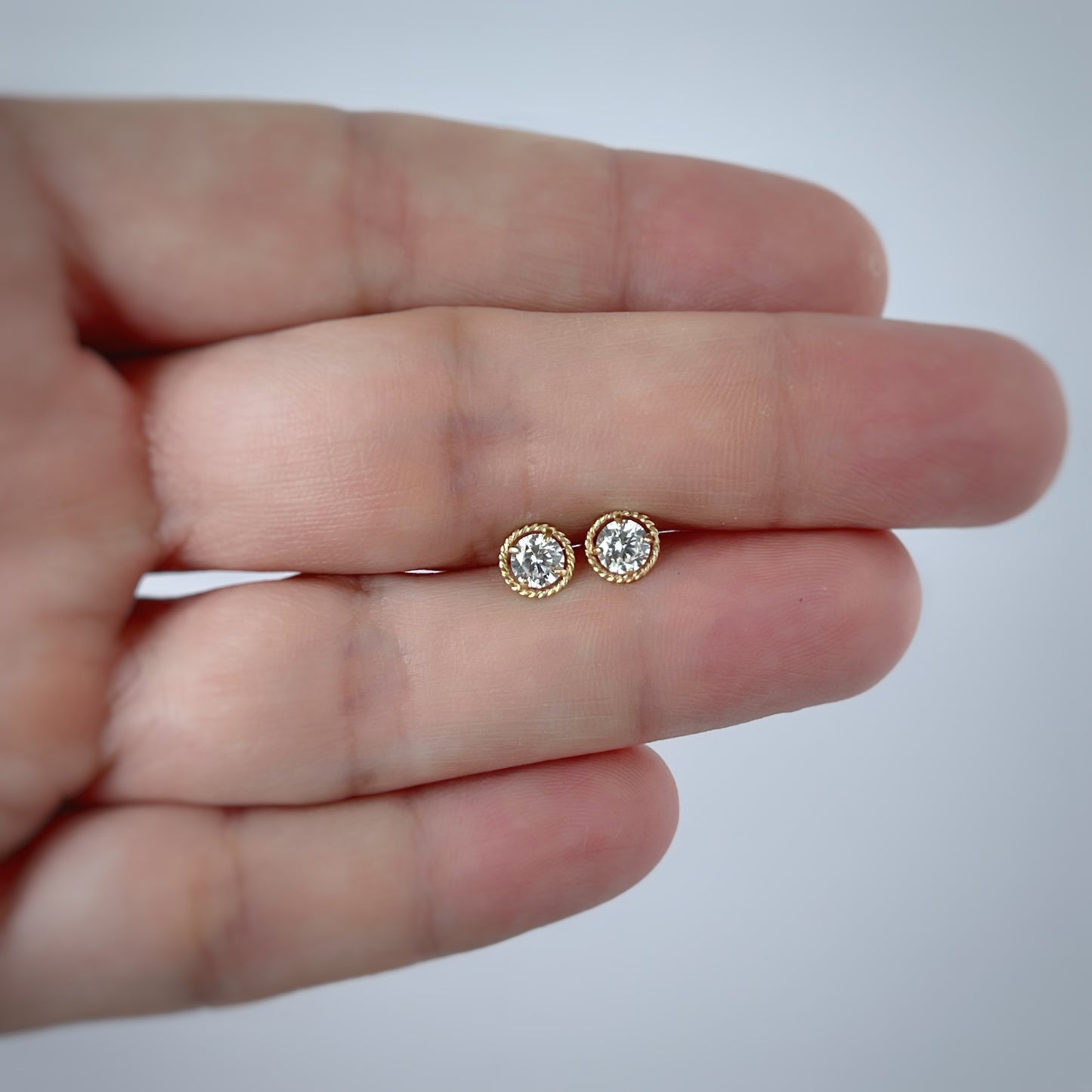 Aretes en oro amarillo 18k con circonita blanca y borde trenzado con broche rosca
