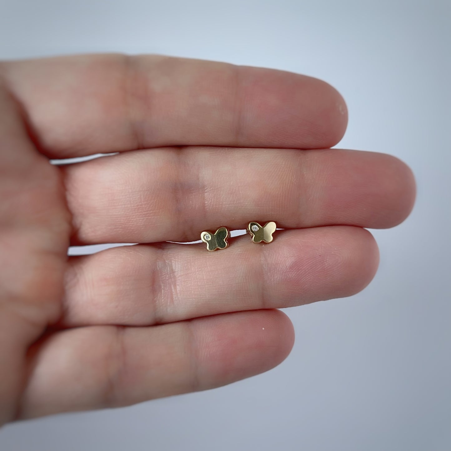 Aretes en oro amarillo 14k con mariposita y un circón con broche rosca