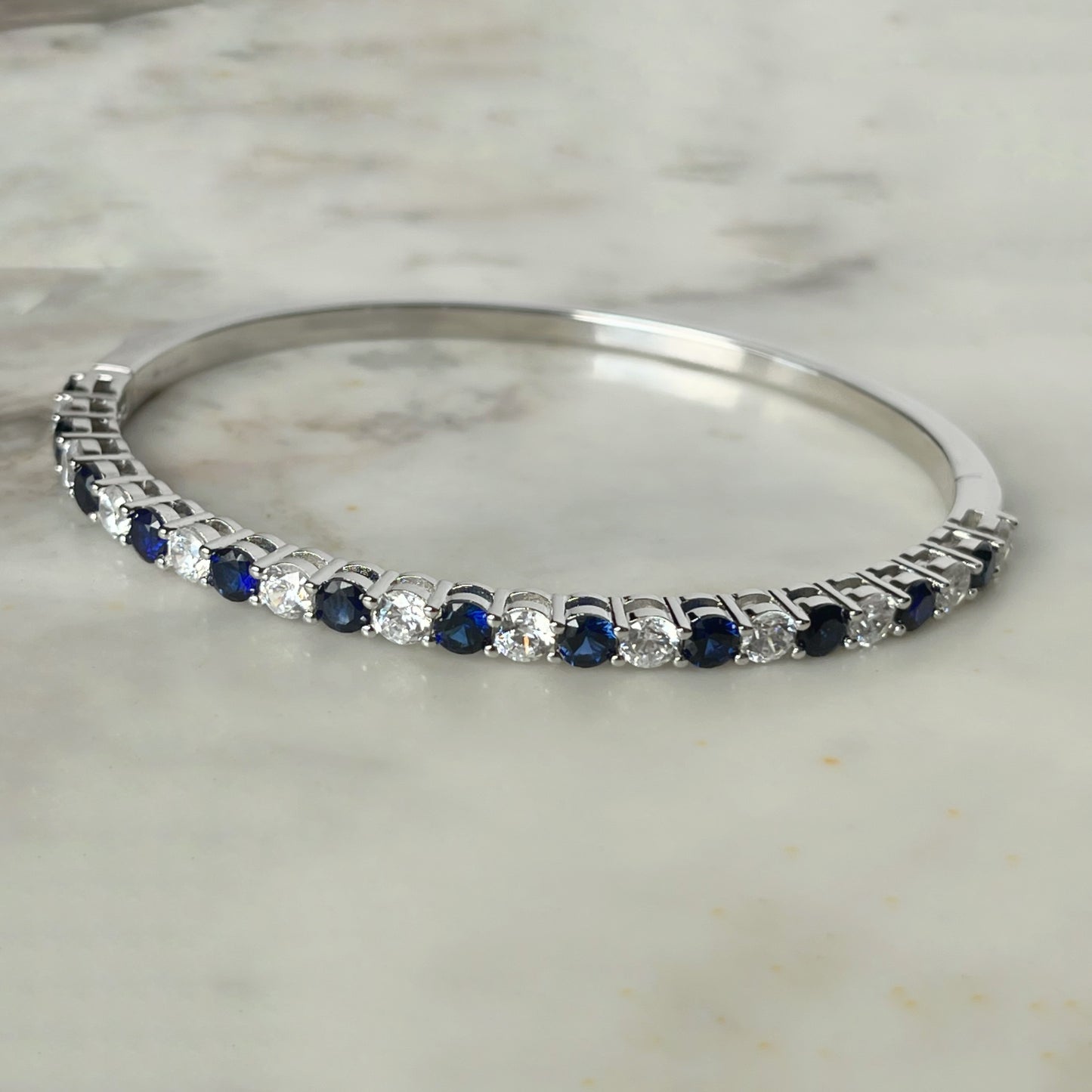Pulsera dura de plata con baño platino y circonita blancas y azul zafiro