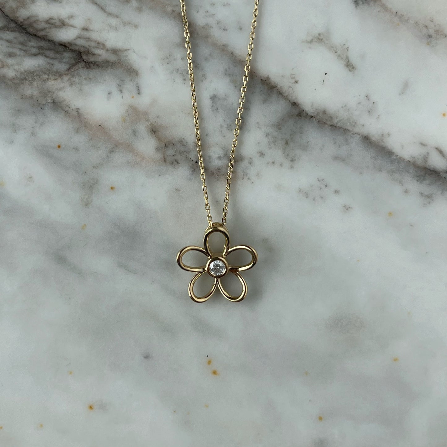 Collar en plata con baño de oro amarillo con dije de flor delineada y diamante central 0.10ct