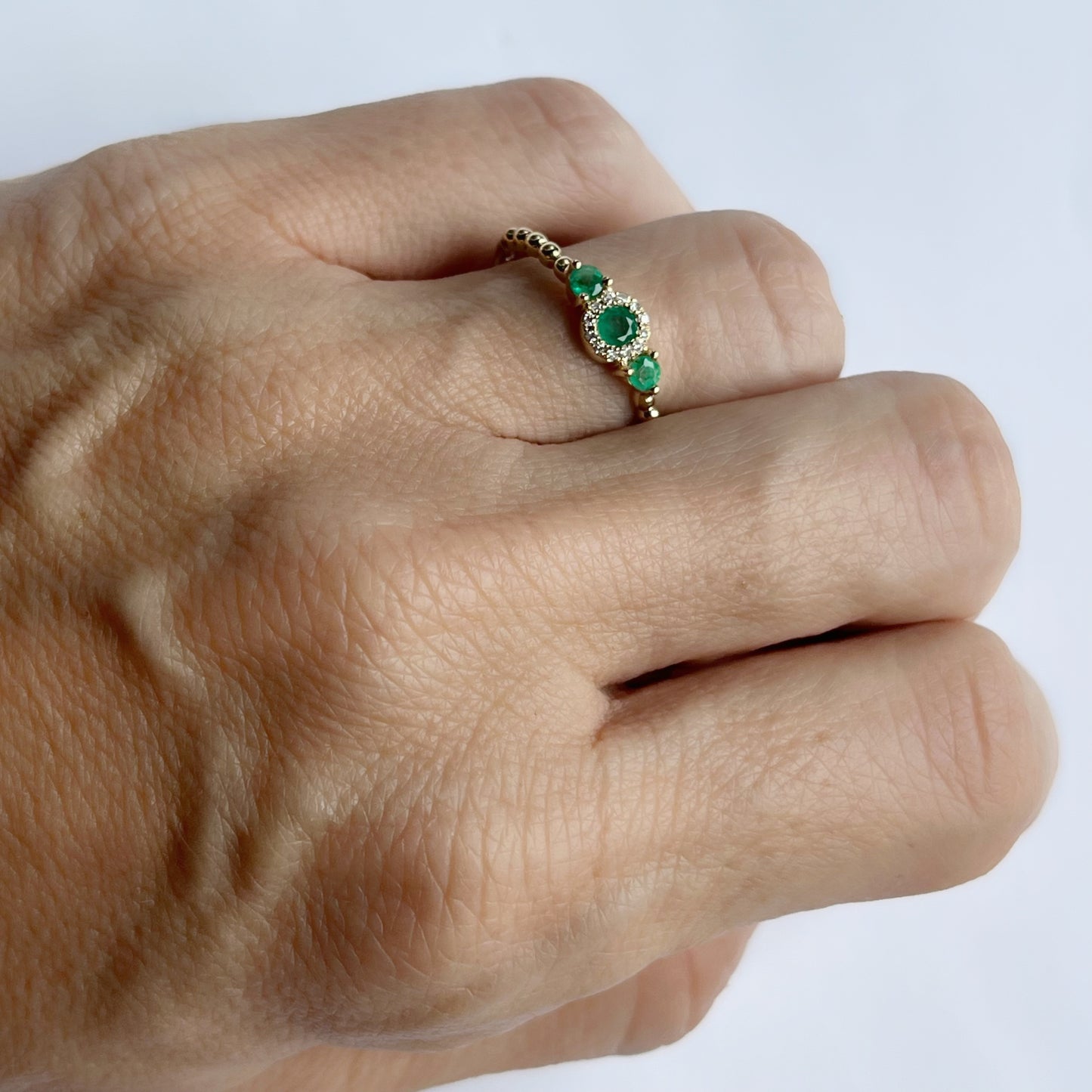 Anillo en oro amarillo 14k con tres esmeraldas redondas 0.25ctw y diamantes 0.04ct con aro de bolitas