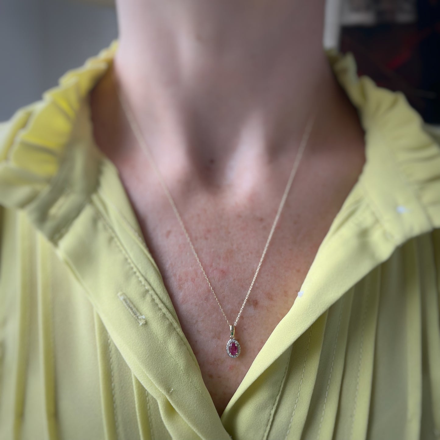 Collar en oro amarillo 10k con dije de rubí ovalada y halo de diamantes.05ctw