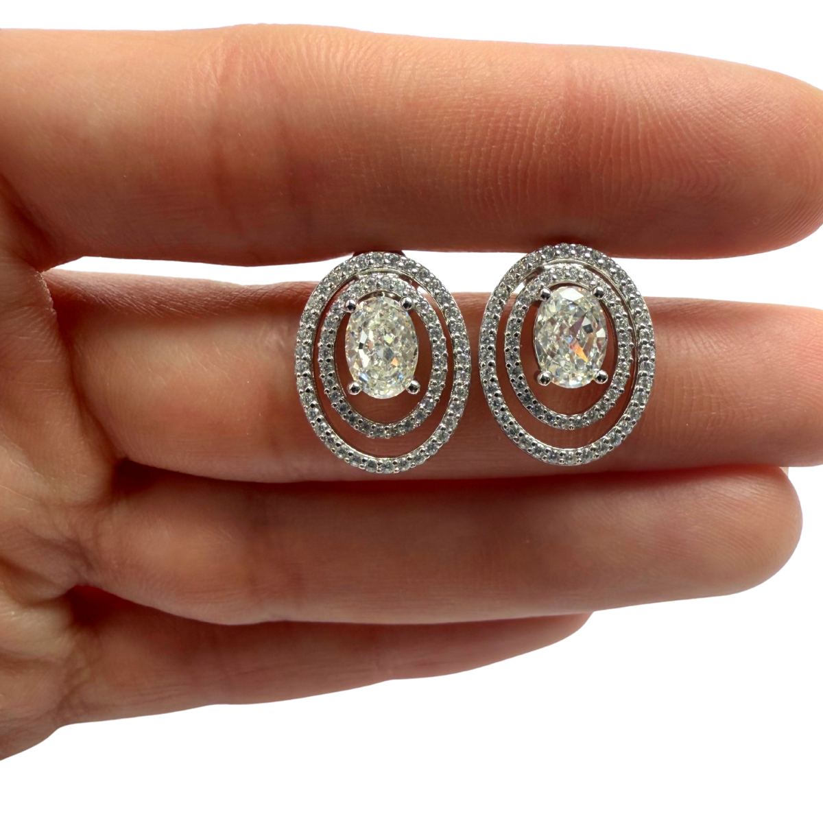Aretes de plata con baño platino y circón ovalado y doble halo espaciado de circonitas