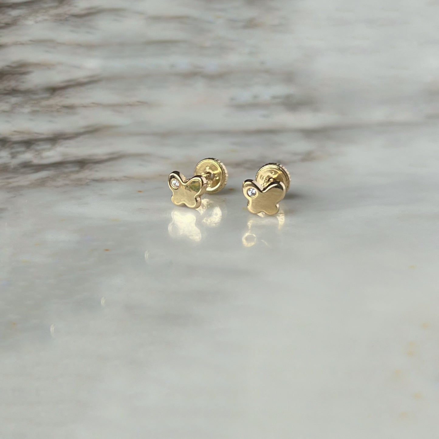 Aretes en oro amarillo 14k con mariposita y un circón con broche rosca