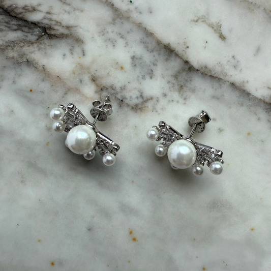 Aretes de plata con baño platino y media flor con perla en el centro y circonitas