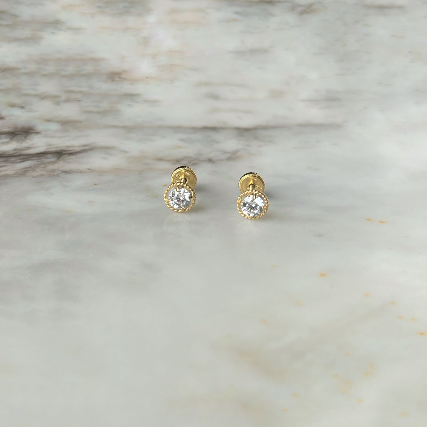 Aretes en oro amarillo 18k con circonita blanca y borde trenzado con broche rosca