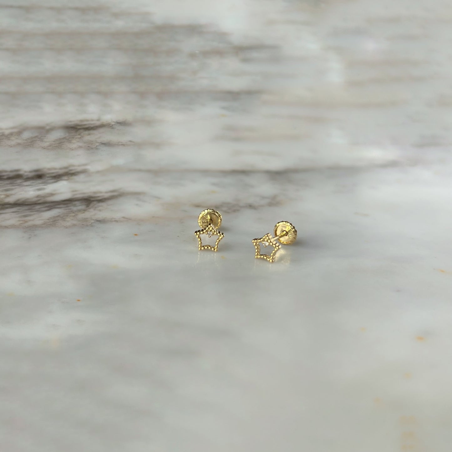 Aretes en oro amarillo 18k estrellita delineada con diamante con broche rosca