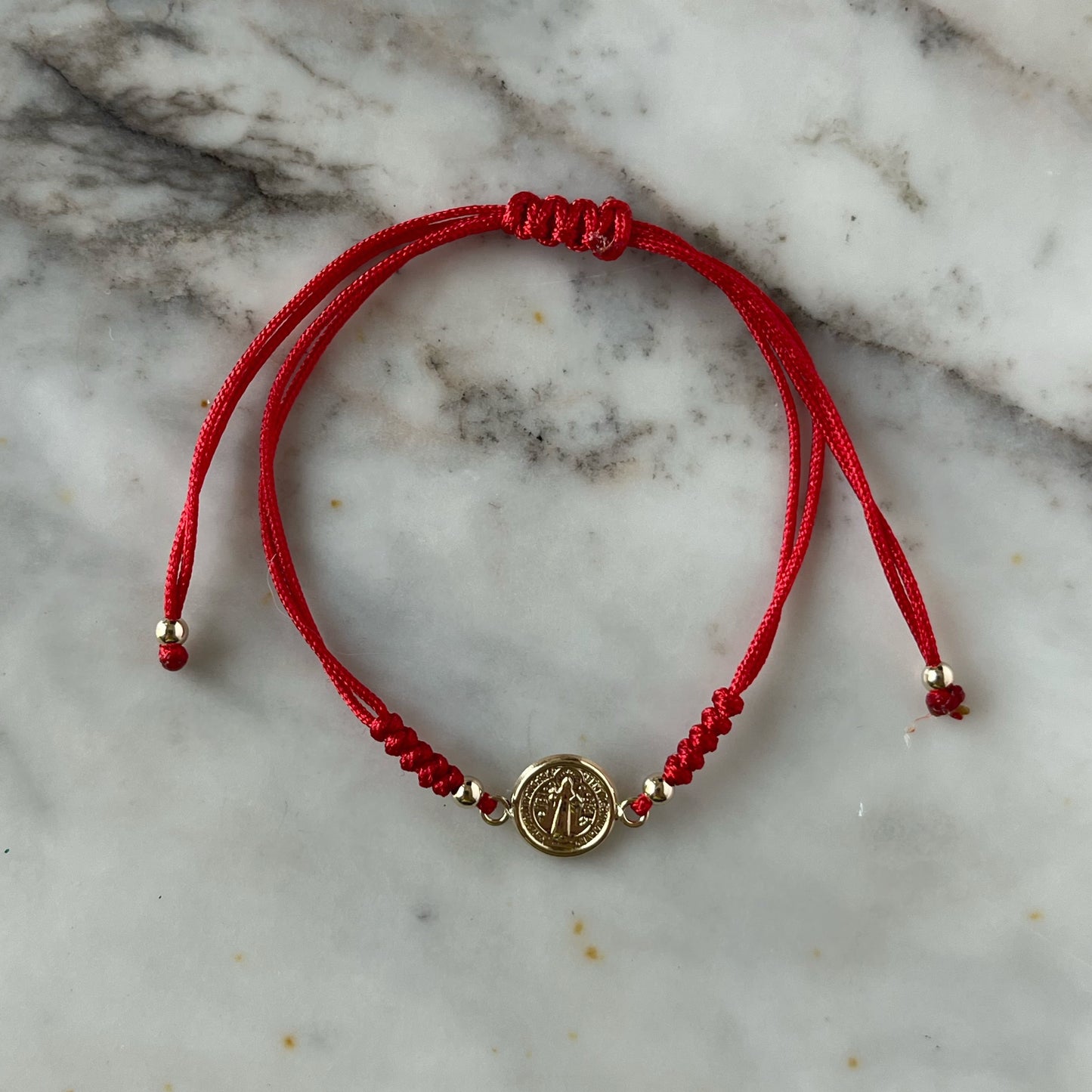 Pulsera de San benito en oro amarillo de 14K con cordón rojo
