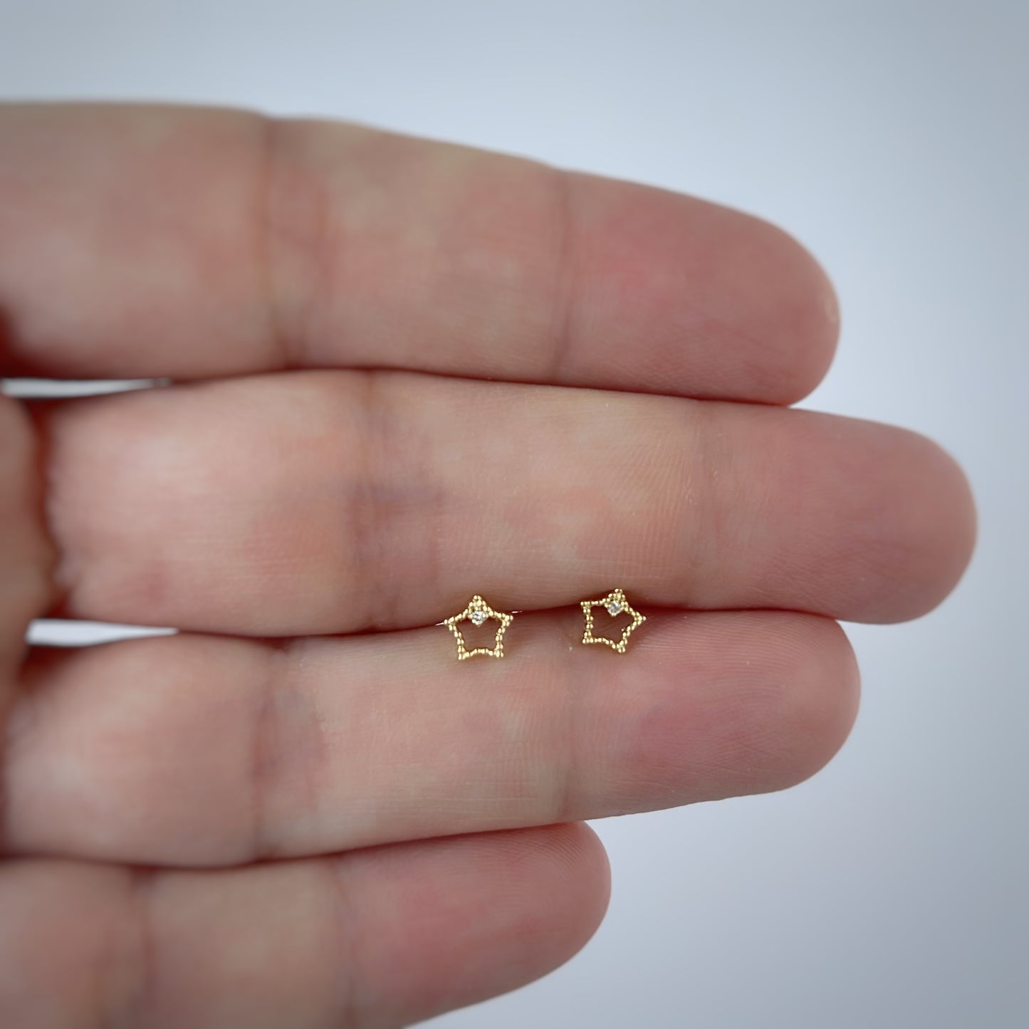 Aretes en oro amarillo 18k estrellita delineada con diamante con broche rosca