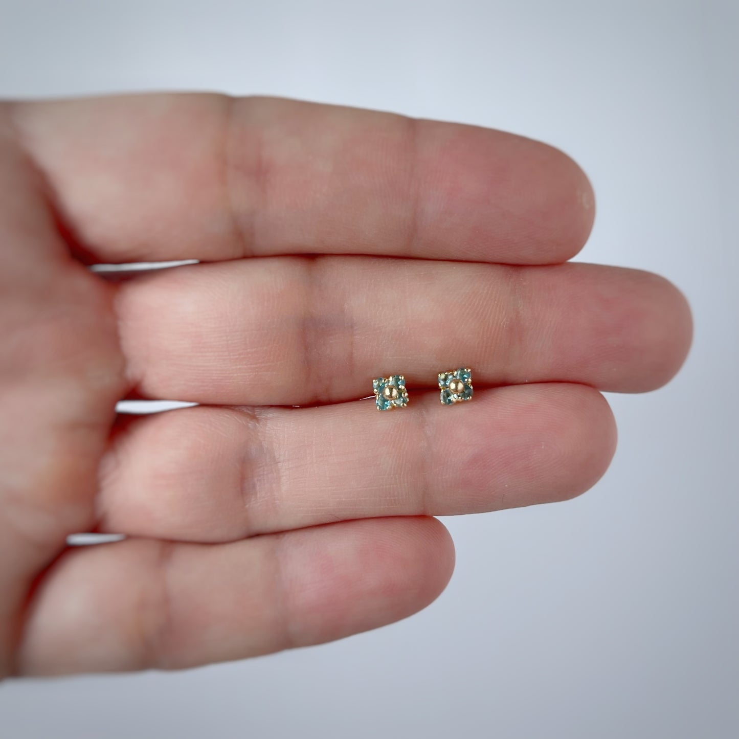 Aretes en oro amarillo 14k flores de circonitas celeste con bolita de oro en el centro con broche rosca