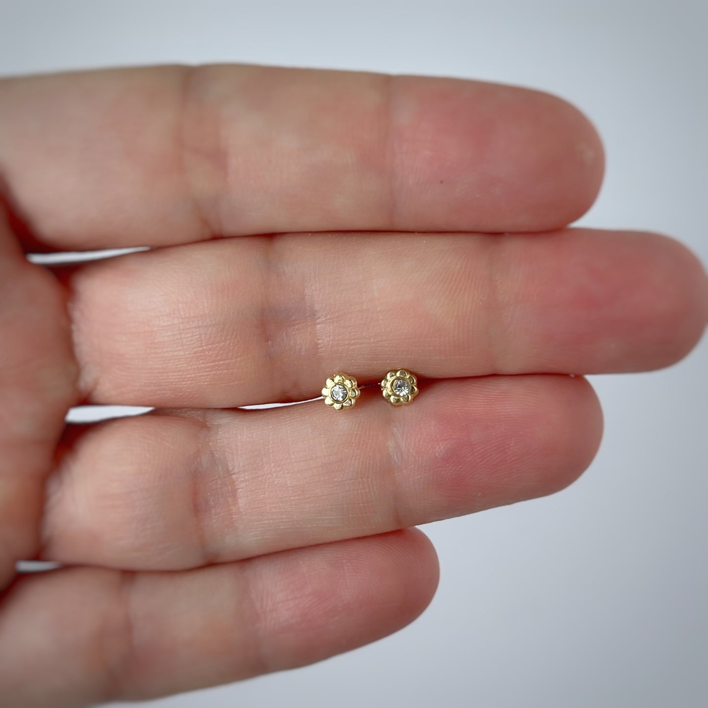 Aretes en oro amarillo 14k de flor mini con circón en el centro con broche rosca