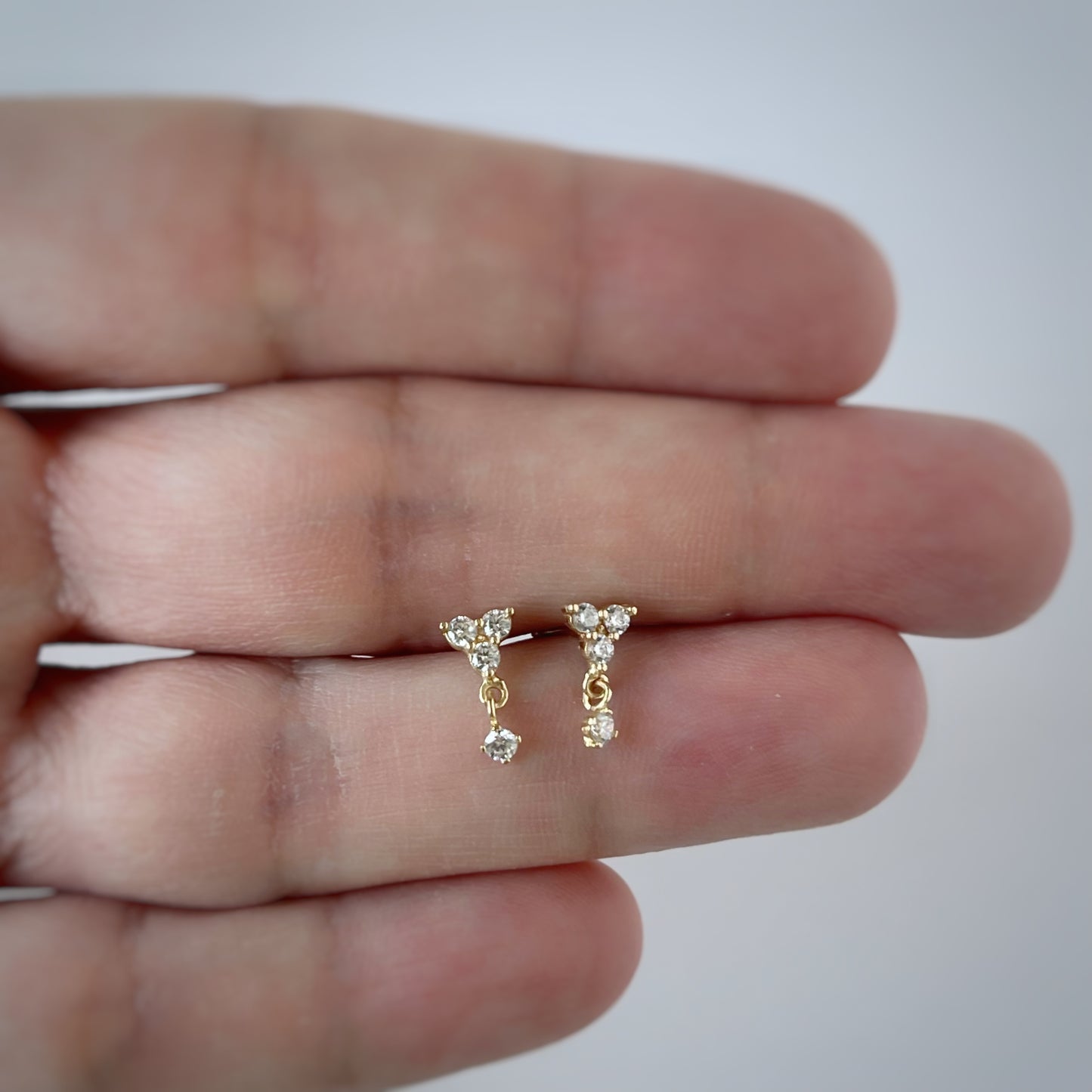 Arete single con tres circonitas blancas y una circonita colgante en oro amarillo de 14K con tope rosca