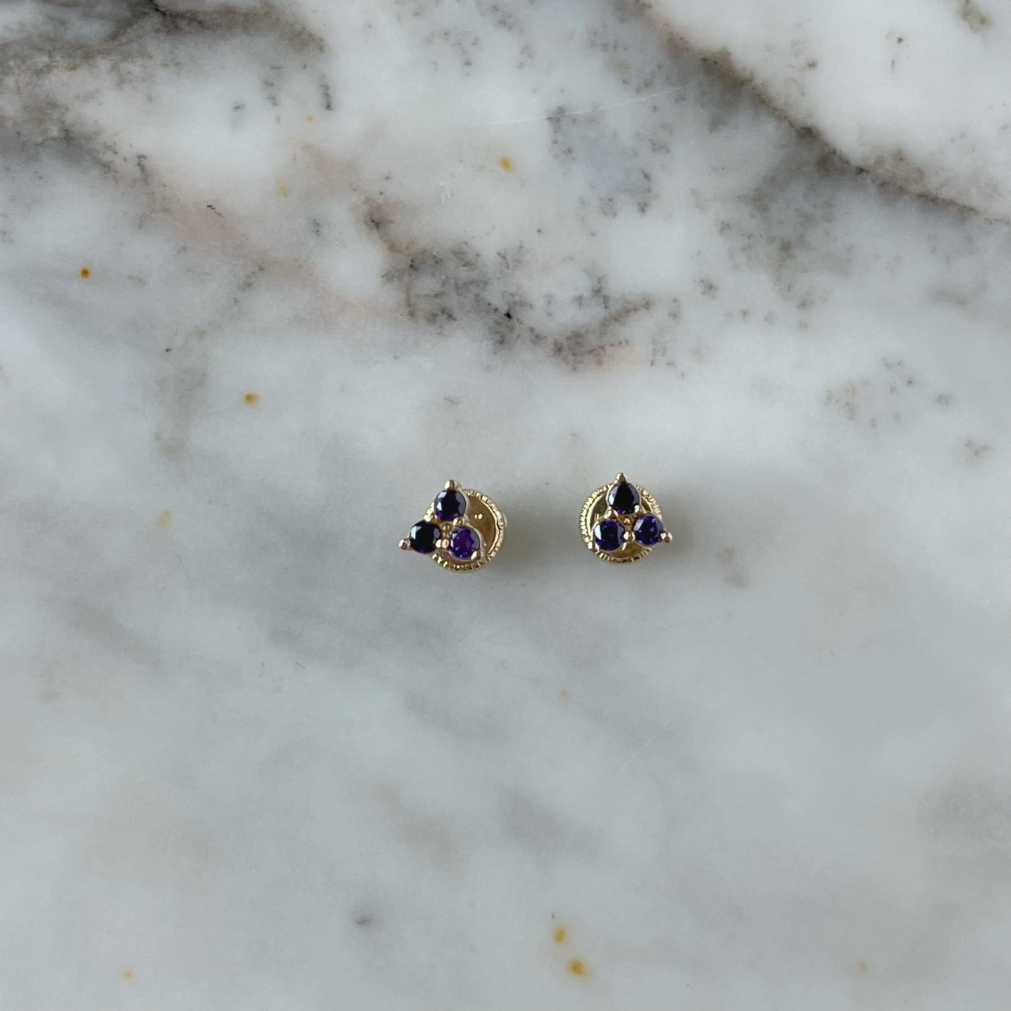 Aretes tres circonitas de color morado en oro amarillo de 14k con tope rosca
