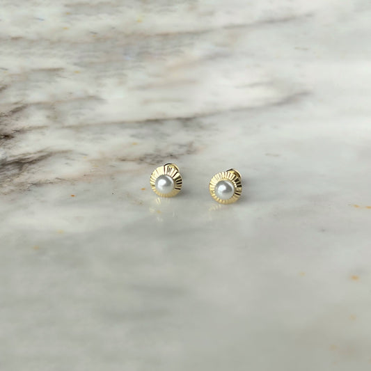 Arete en oro amarillo 14K con perla en el centro y círculo de rayitas de oro alrededor con tope rosca