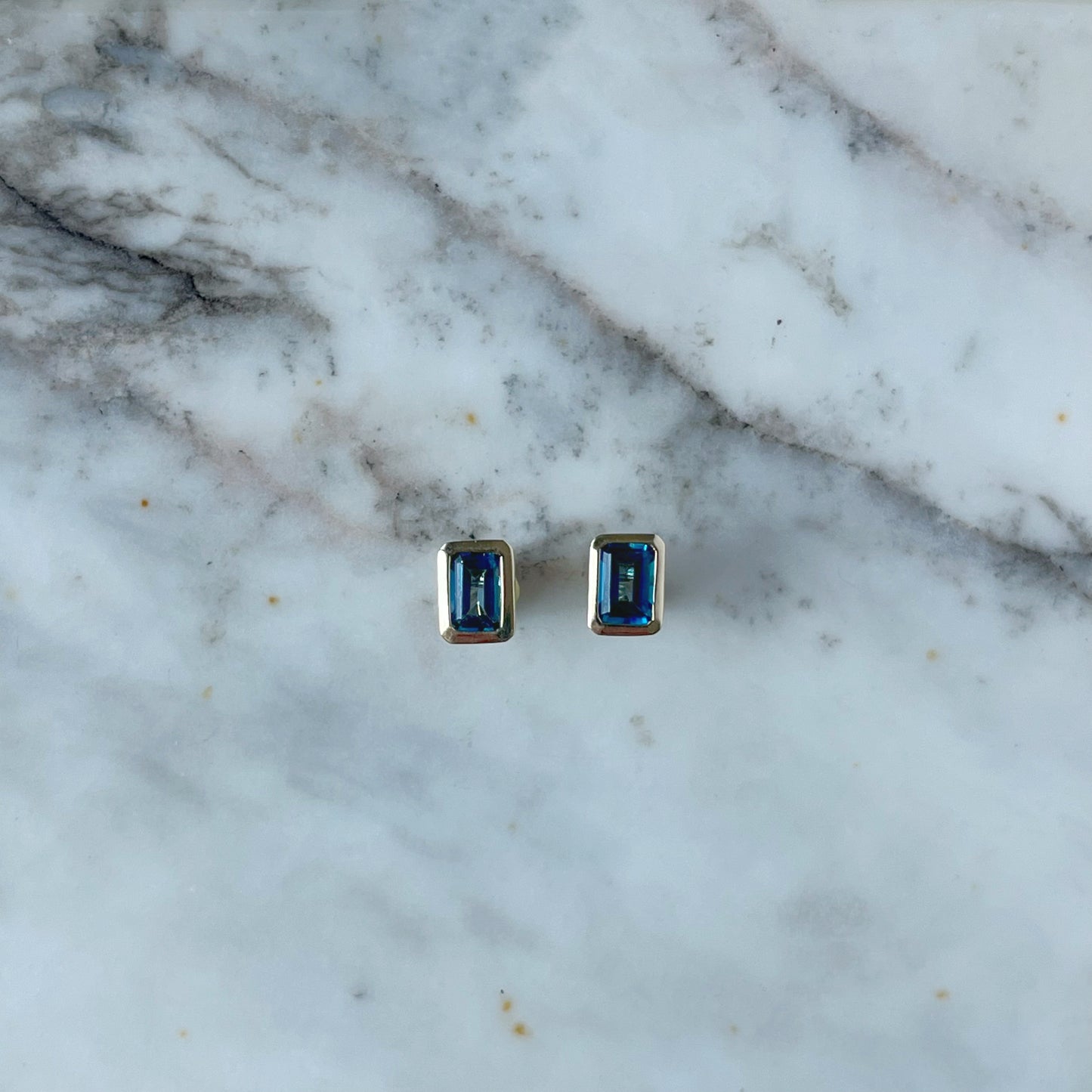 Arete en oro amarillo 10K con topacio london blue rectangular biselado