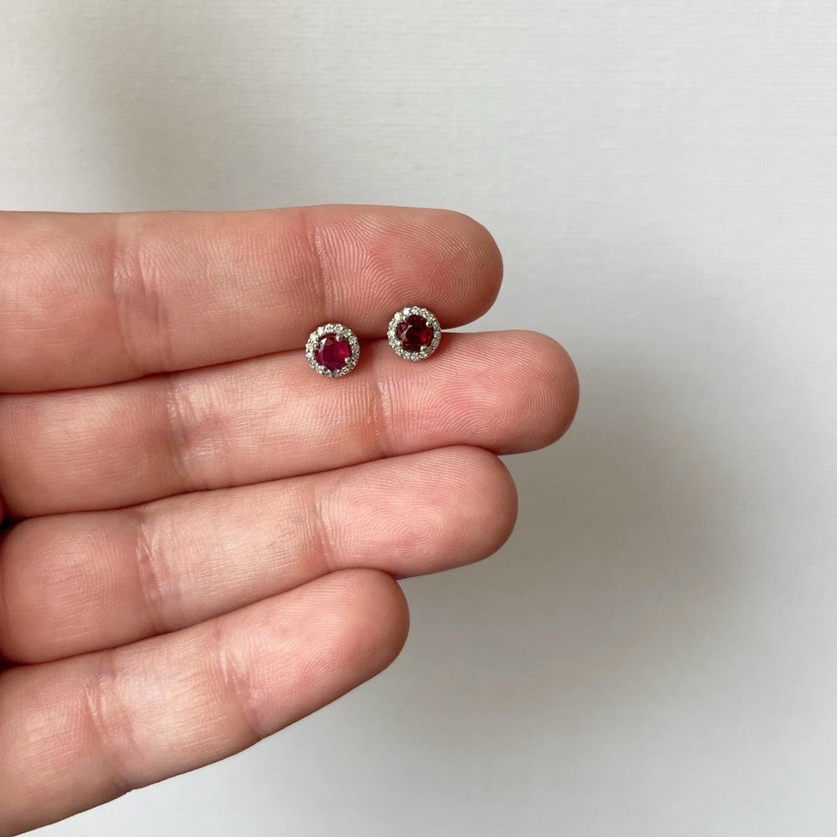 Aretes redondos en oro blanco 10k con rubíes y halo de diamantes 0.10ctw