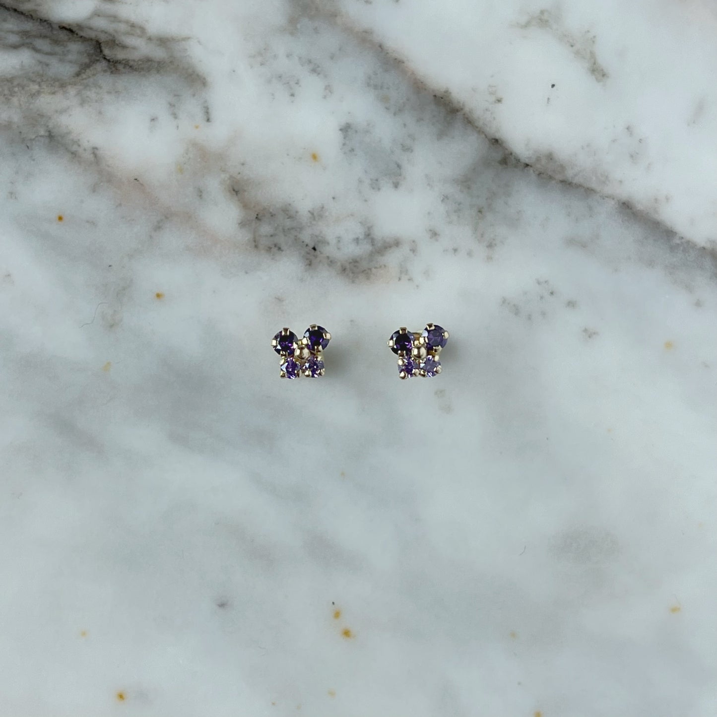 Aretes en oro amarillo 14k con mariposita de circonitas moradas con broche rosca