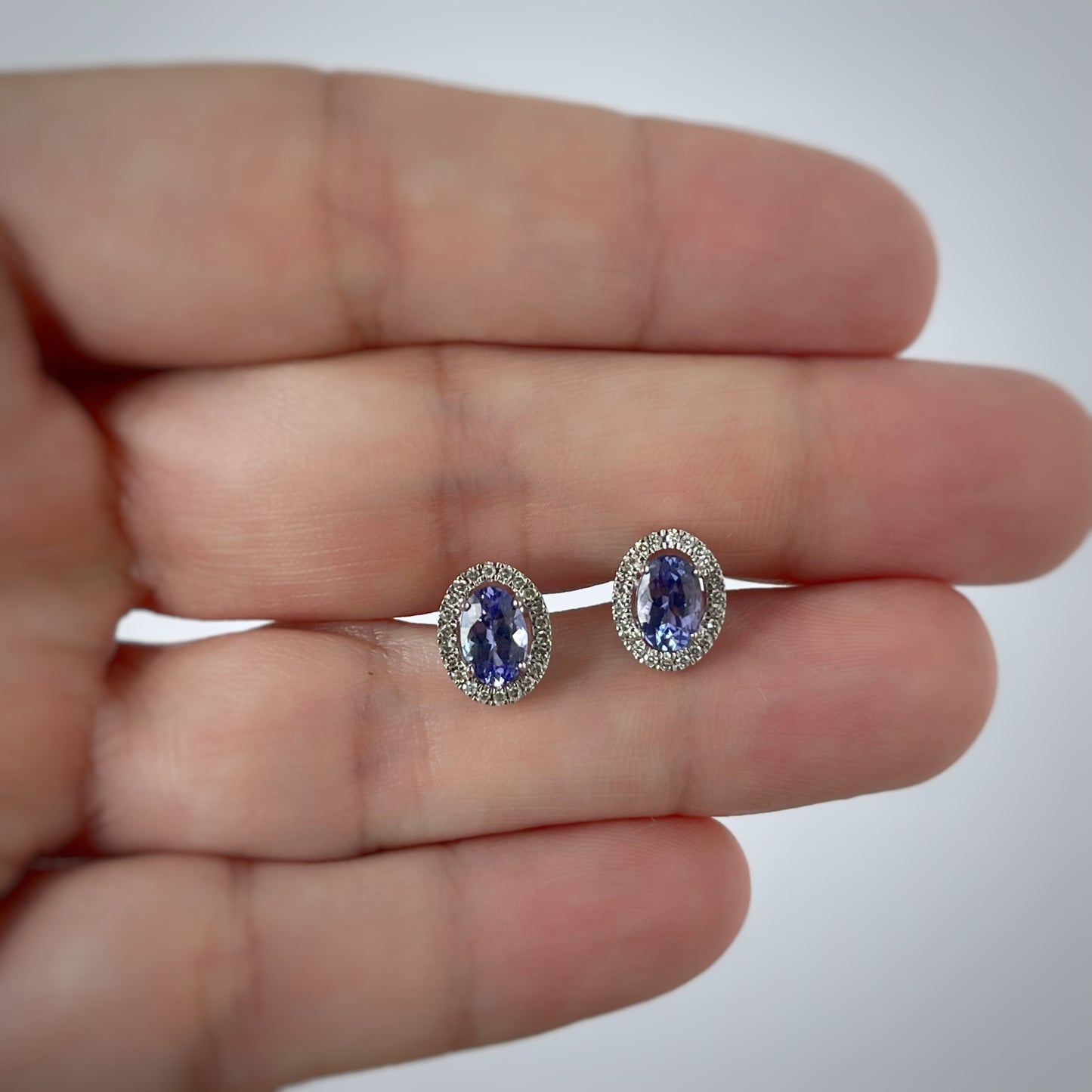 Aretes en oro blanco 10k con tanzanita ovalada y halo de diamantes 0.18ctw con tope rosca