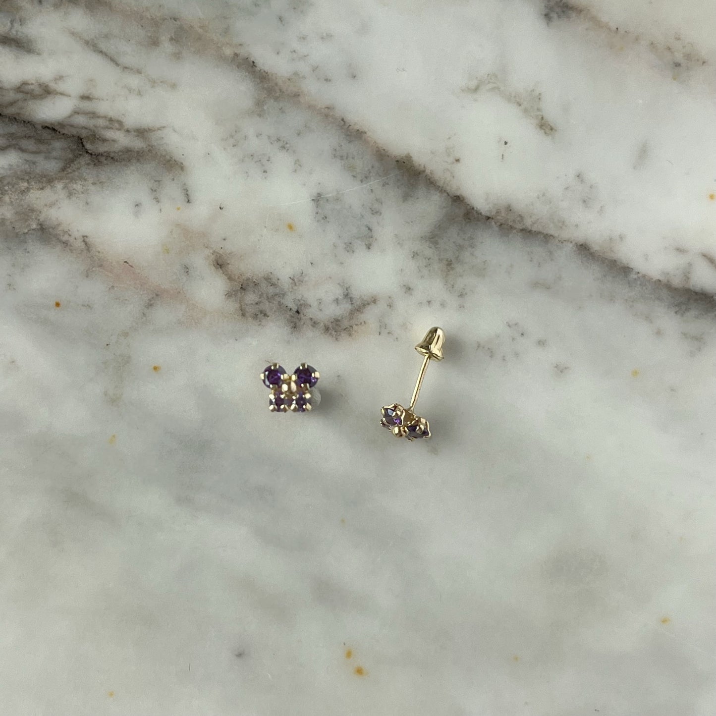 Aretes en oro amarillo 14K con mariposa con circonita morada con dos tonos y bolita de oro en el centro con tope rosca