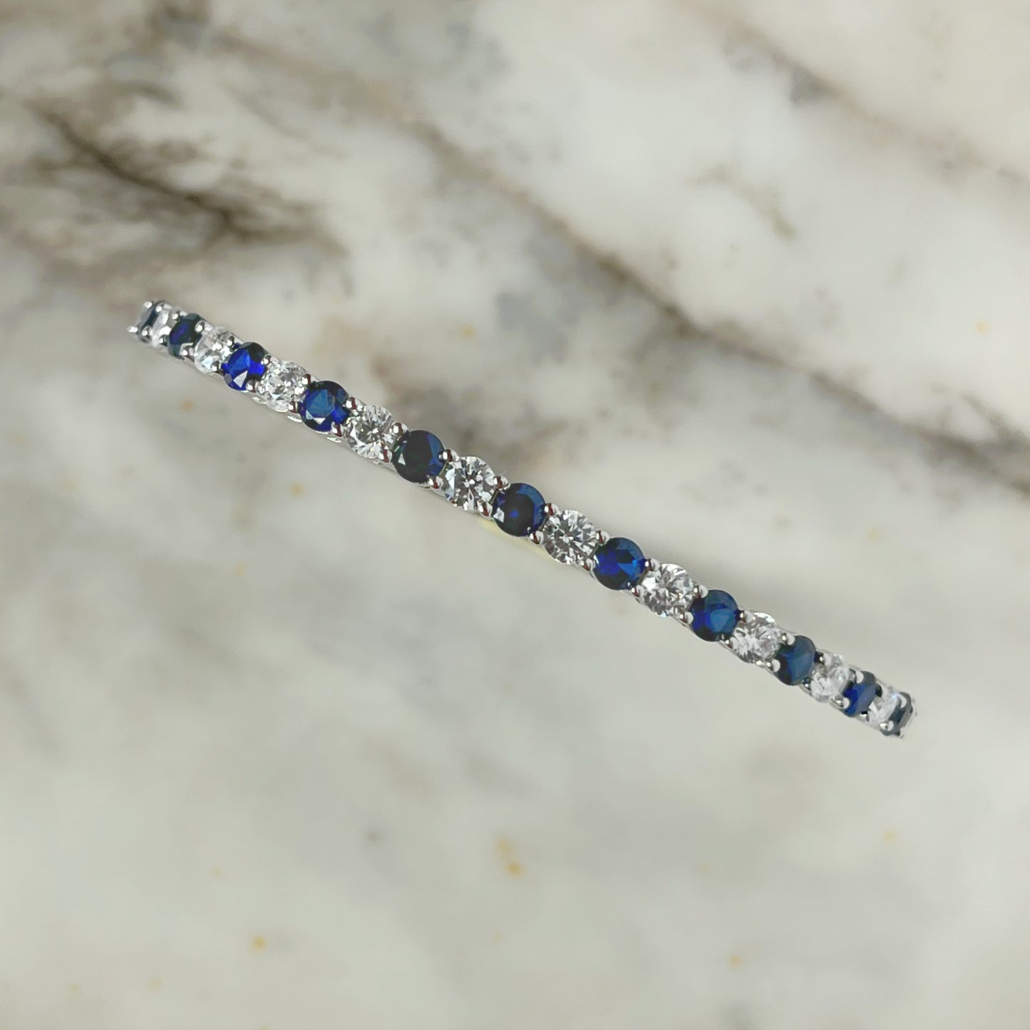 Pulsera dura de plata con baño platino y circonita blancas y azul zafiro